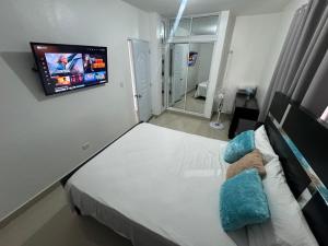 a bedroom with a bed with a tv on the wall at Hermoso Apartamento en 3er nivel con terraza privada in Bonao