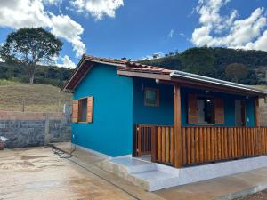 a blue house with a wooden porch at Rancho do Léo in Conceição do Mato Dentro