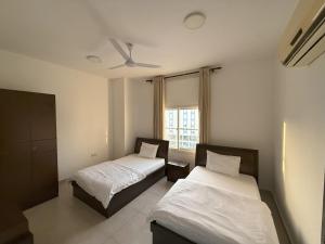 塞拉莱أجنحة هومينج ــ Homing Suites的有两张床和一扇窗户的卧室