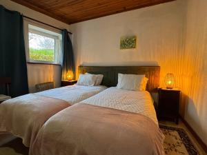 two beds in a bedroom with two lamps and a window at Escapada na Natureza - Charmoso Refúgio nas Alturas in Góis +38 photos