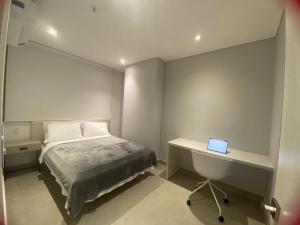 a bedroom with a bed and a desk with a laptop at Exclusivo Apartamento en Distrito 90 in Barranquilla