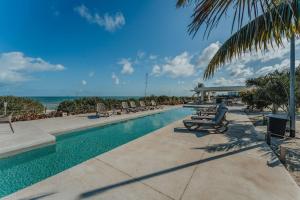 a swimming pool with lounge chairs and the ocean at Departamento con vista al mar . in Telchac Puerto