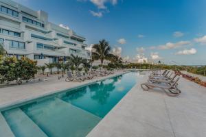 a swimming pool with lounge chairs and a building at Departamento con vista al mar . in Telchac Puerto