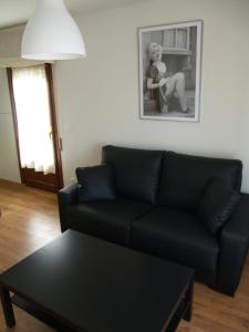 sala de estar con sofá negro y mesa en Apartamentos Las Casitas de El Blasón, en Coca