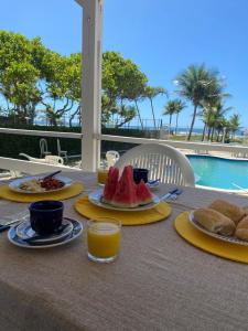 Sol Mar Hostel في Santo Agostinho: طاولة مع أطباق من الطعام والمشروبات ومسبح