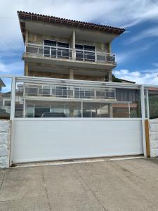 a white privacy fence in front of a house at Casa pôr do sol in São Pedro da Aldeia