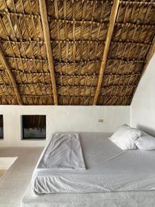 a bed in a room with a straw roof at Blue Beach Eco-Hotel by Sanfabini in Bayahibe