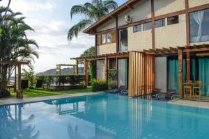 a swimming pool in front of a house at El Shadday Pousada Boutique in Ubatuba