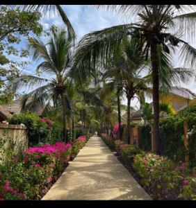 a pathway with palm trees and flowers in a garden at Villa dans Residence du Port in Saly Portudal +31 photos