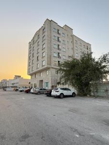 塞拉莱أجنحة هومينج ــ Homing Suites的一座大楼，停车场里停满了汽车