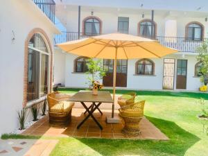 a table with an umbrella in the yard of a house at Casa AmaNacer Malinalco in La Ladrillera
