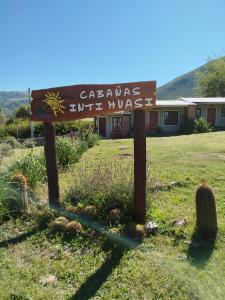 a sign in a field with a building in the background at Cabañas Inti Huasi in Tafí del Valle