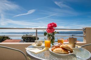 a table with a plate of bread and a vase of roses at Apartments Villa Stari Koko in Omiš
