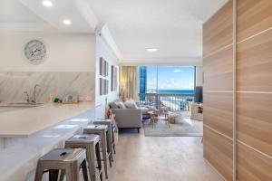 cocina con barra con taburetes y sala de estar en Beach retreat with balcony and views, en Gold Coast
