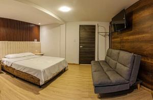 a bedroom with a bed and a couch and a television at Hotel 168 Pasto in Pasto