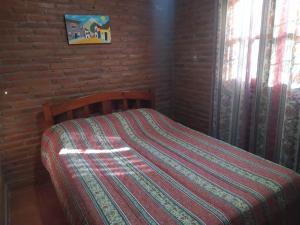 a bed in a room with a red brick wall at Cabañas Inti Huasi in Tafí del Valle