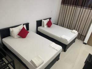 two beds with red pillows in a room at Saliyawewa Cabins in Kala Oya