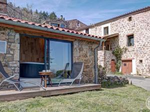 una casa con terrazza arredata con tavolo e sedie di Gîte de charme 18ème avec spa et terrasse, St-Julien-Molin-Molette - FR-1-496-335 a Saint-Julien-Molin-Molette