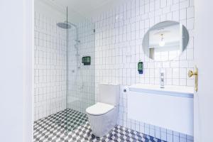 a white tiled bathroom with a toilet and a sink at The Lakes Hotel, Rosebery in Sydney +23 photos