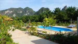 a resort swimming pool with mountains in the background at Khao Sok Jasmine Garden Resort - SHA Certified in Khao Sok National Park