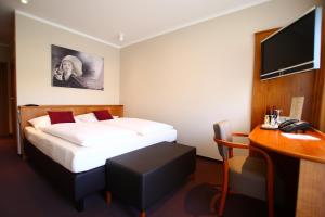 a hotel room with a bed and a desk with a computer at Hotel Straubs Schöne Aussicht in Klingenberg am Main