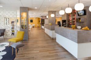 a lobby of a pharmacy with yellow chairs and a counter at Kyriad Saint-Etienne Centre in Saint-Étienne