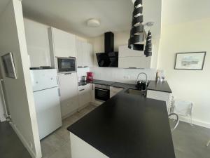eine Küche mit weißen Geräten und einer schwarzen Arbeitsplatte in der Unterkunft T3 face plage avec balcon et parking, aux Sables-d'Olonne - FR-1-92-808 in Les Sables-dʼOlonne