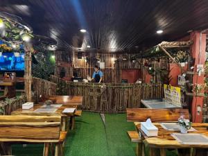 un restaurant avec des tables en bois et une personne en arrière-plan dans l'établissement Buffalo Bill Hotel Koh Chang, à Ko Chang