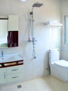 a bathroom with a shower and a toilet and a sink at Putian Meizhou Island Lanhai Hotel in Putian