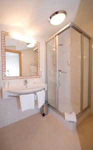 a bathroom with a shower and a sink and a mirror at Vital - und Wellnesshotel Hanneshof in Filzmoos
