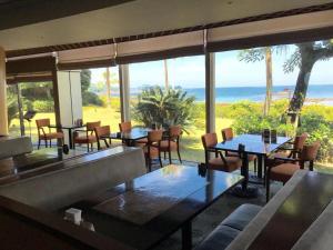 ein Restaurant mit Tischen und Stühlen und Blick auf das Meer in der Unterkunft Hotel Harvest Nankitanabe in Kitahara