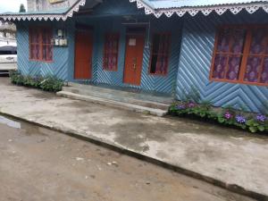 ein blaues Haus mit roten Türen und Blumen in der Unterkunft EHI Homestay Rishop in Rishop