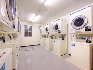 a laundry room with white appliances and white cabinets at La'gent Inn Kesennuma in Higashi-hachimammae