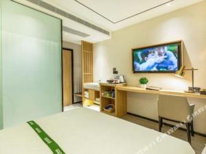 Una habitación de hotel con una cama y un televisor en la pared. en GreenTree Inn Shandong Jinan Suncun New District Express Hotel, en Jinan
