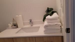 a bathroom with a sink and a stack of towels at Modern Suite Near Hamilton Airport in Hamilton