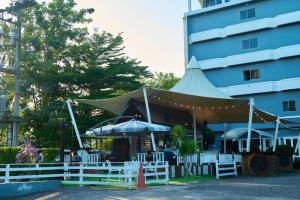 a building with a tent and tables and umbrellas at Nora Bukit Hotel in Ban Sam Kong