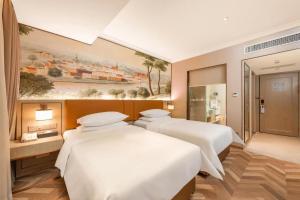 two beds in a room with a painting on the wall at Vienna Hotel 5.0 Qingyuan City Plaza Lianjiang Road in Qingyuan +274 photos