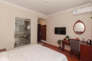 GreenTree Inn Wuxi Donggang Town Donghutang Shell Hotel في ووشي: غرفة نوم بها سرير ومكتب ومرآة