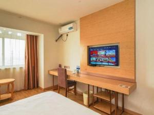 ein Hotelzimmer mit Schreibtisch und Fernseher an der Wand in der Unterkunft GreenTree Inn Suzhou North Zhongshan Road Weiye Yingchun Plaza Business Hotel in Suzhou