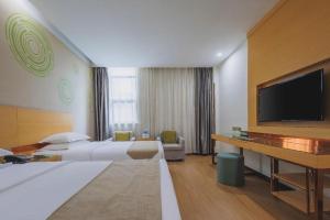 une chambre d'hôtel avec deux lits et une télévision à écran plat dans l'établissement GreenTree Inn Hefei Feidong County High Speed Rail Station Wuyue Plaza Express Hotel, à Feidong