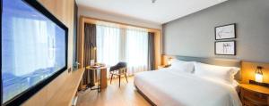 a hotel room with a bed and a desk and a television at Ueasy Hotel The Mixc in Nanning +31 photos