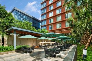 a hotel patio with tables and chairs and umbrellas at Four Points by Sheraton Haikou International Airport in Haikou