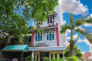a white building with a palm tree in front of it at OYO 236 Penginapan Rumah Hijau in Sukarami