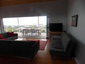 a living room with a couch and a table with chairs at By the Sea Vacation Home in Brenton-on-Sea