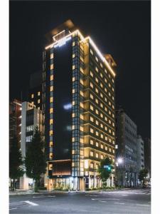 a tall building with lights on it at night at Hotel Yaenomidori Tokyo in Tokyo