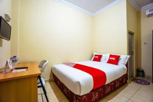 a bedroom with a bed with red pillows and a desk at OYO 1720 A2b Residence in Malalayang