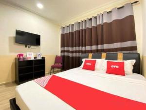 a bedroom with a bed with red pillows and a tv at OYO 90324 Muar Station Hotel in Pantai Cenang
