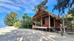 a small hut on a beach with the ocean at Raja Ampat Lovely homestay in Pulau Yefbie