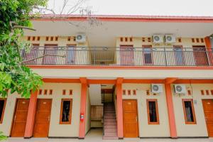 ein Gebäude mit orangefarbenen Türen und einem Balkon in der Unterkunft Hotel O Panderman Residence in Karangtengah