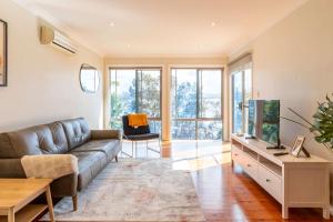 a living room with a couch and a tv at Bay and Beachside Family Retreat in Killcare